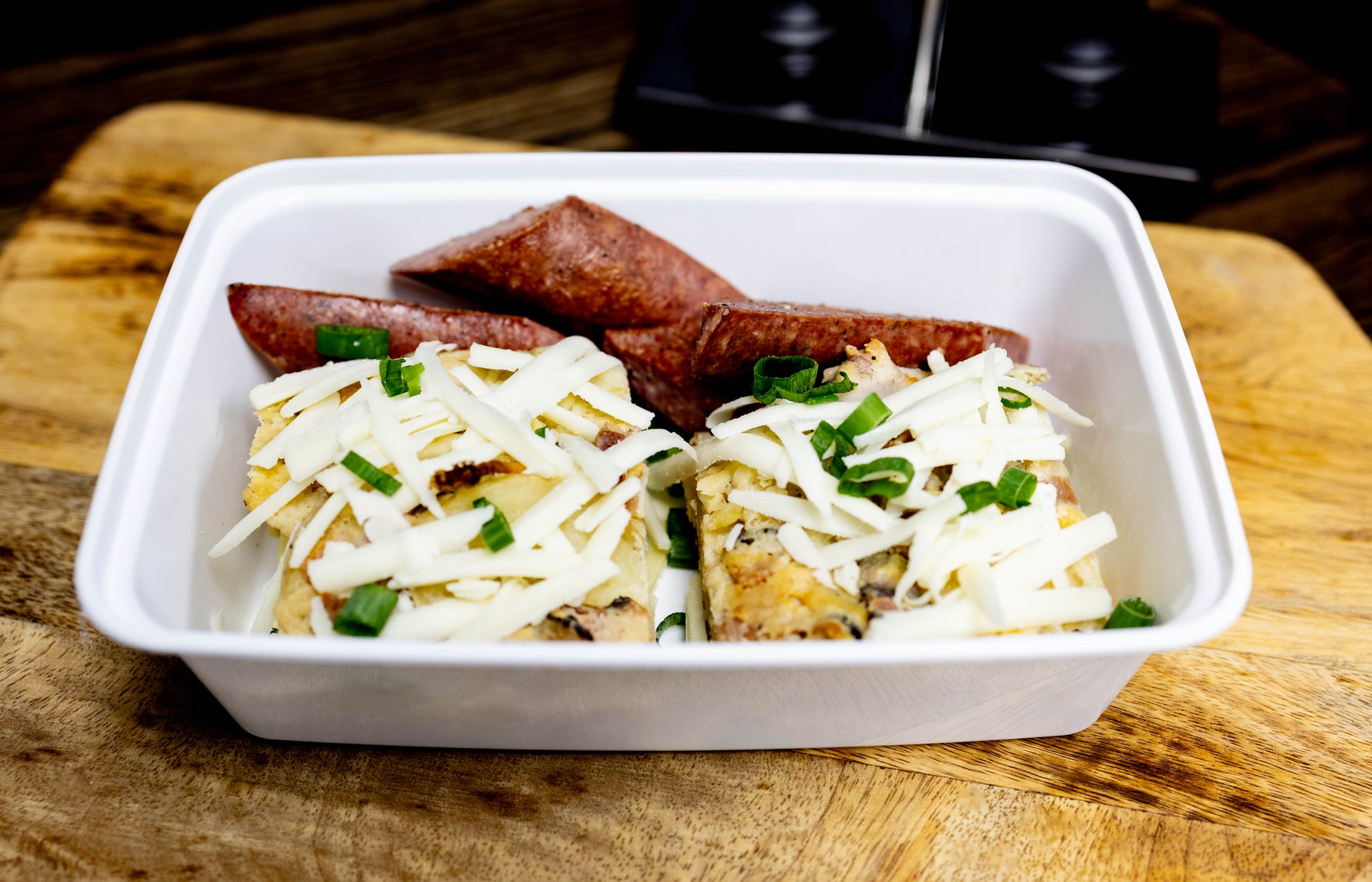 Container with cheesy breakfast casserole and sausages, designed for grab-and-go easy meal planning.