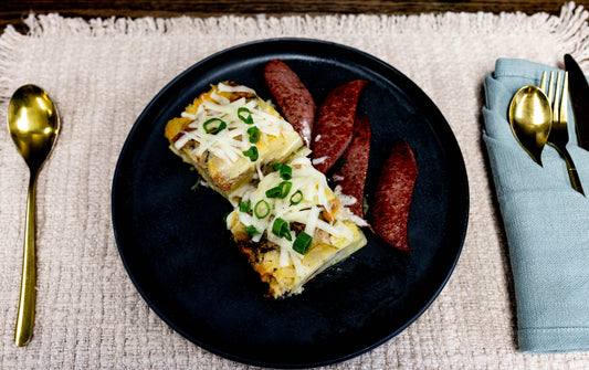 Cheesy breakfast casserole with sausage slices on a black plate-ideal for easy meal planning.