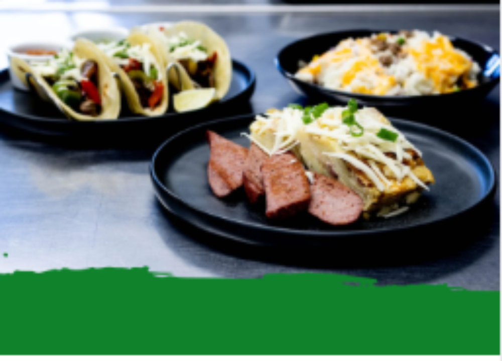 Assorted tacos and protein-packed dishes on black plates showcasing fresh, convenient meal prep services.